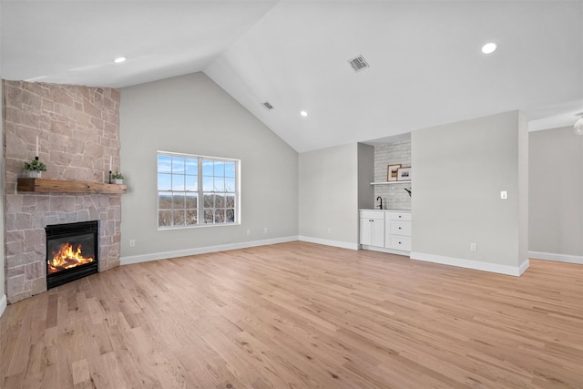 unfurnished living room with a large fireplace, visible vents, baseboards, and light wood finished floors