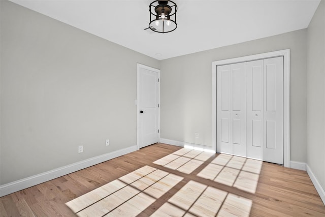 unfurnished bedroom with light wood-type flooring, baseboards, and a closet