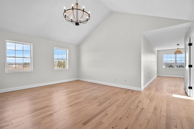 unfurnished room featuring light wood-style floors, baseboards, vaulted ceiling, and an inviting chandelier