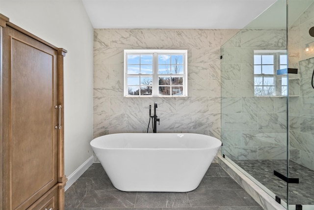 bathroom featuring marble finish floor, baseboards, walk in shower, and a freestanding bath