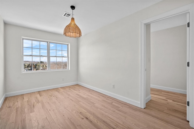 spare room with baseboards, visible vents, and light wood finished floors