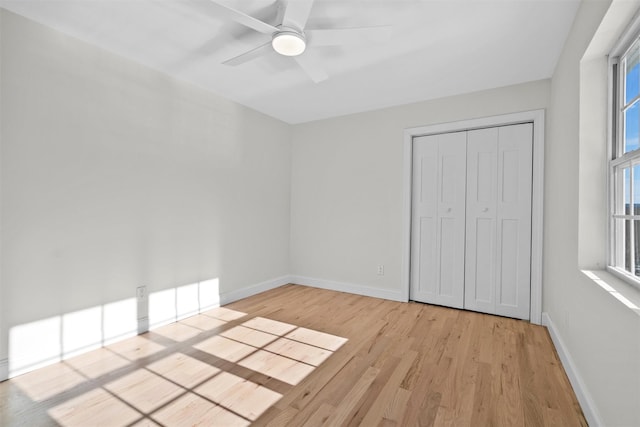 unfurnished bedroom with a ceiling fan, a closet, light wood-style flooring, and baseboards