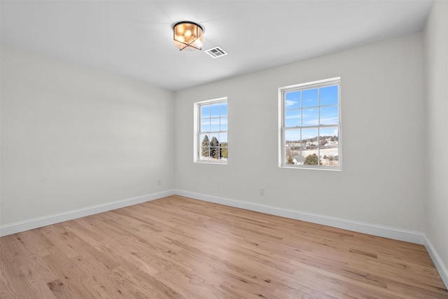 spare room with visible vents, light wood-style flooring, and baseboards