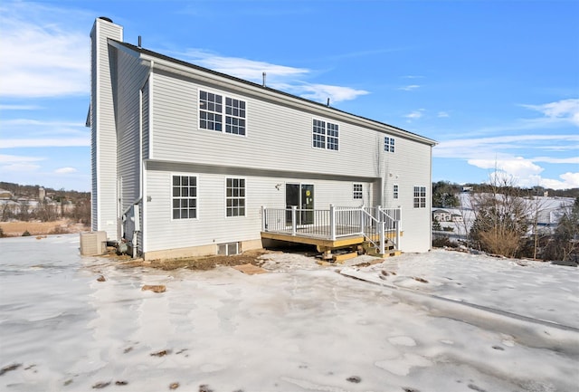 snow covered back of property featuring a deck and a chimney