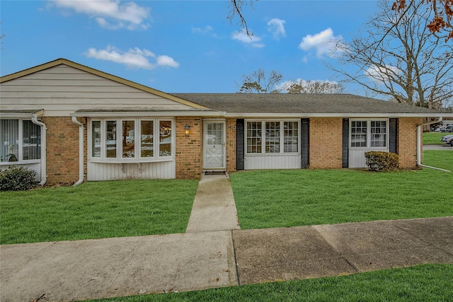 ranch-style house featuring brick siding, a front yard, and a shingled roof