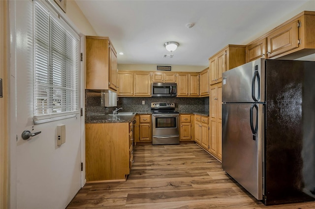 kitchen with visible vents, appliances with stainless steel finishes, backsplash, light wood-type flooring, and a sink