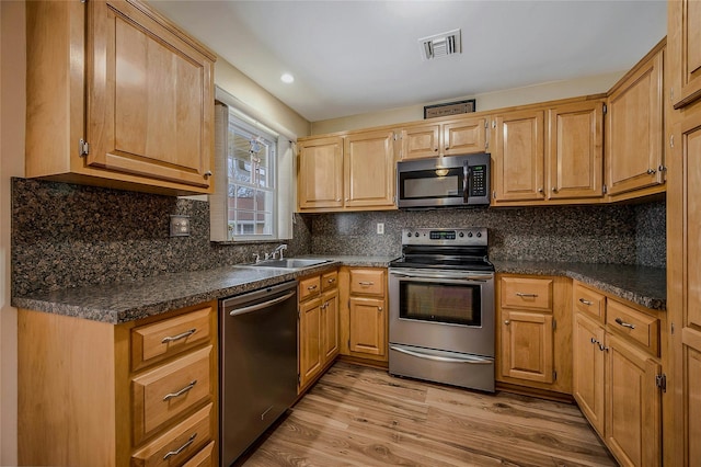 kitchen with light wood finished floors, tasteful backsplash, visible vents, stainless steel appliances, and a sink