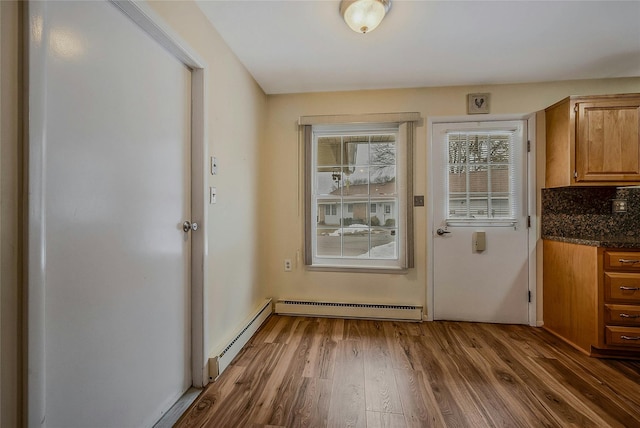 doorway to outside featuring a baseboard heating unit and wood finished floors