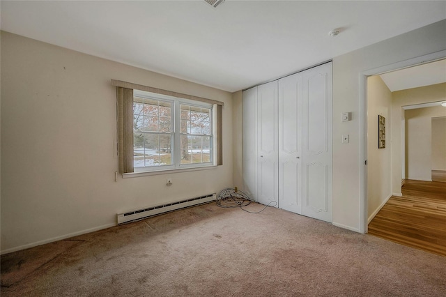 unfurnished bedroom featuring light carpet, a baseboard radiator, baseboards, and a closet