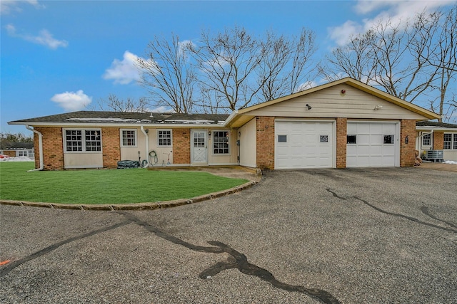 ranch-style house with a front yard, brick siding, driveway, and an attached garage