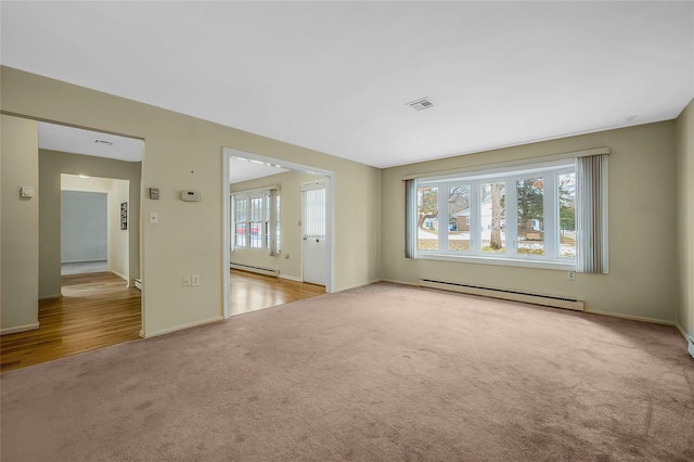 empty room with a baseboard radiator, light colored carpet, visible vents, and baseboards