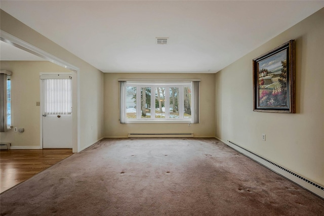 carpeted spare room with a baseboard heating unit, a baseboard radiator, and visible vents