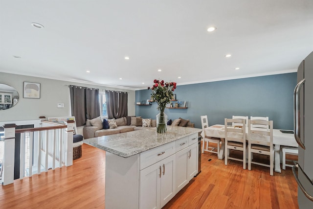 kitchen featuring stainless steel fridge, a center island, light stone counters, white cabinets, and light wood-type flooring