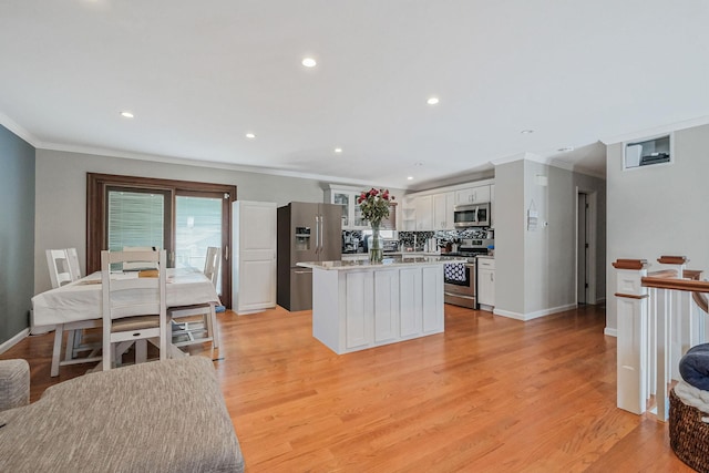 kitchen featuring stainless steel appliances, light wood-type flooring, a kitchen island, and white cabinets