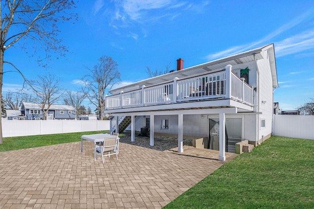 rear view of house with a wooden deck, a patio area, and a lawn