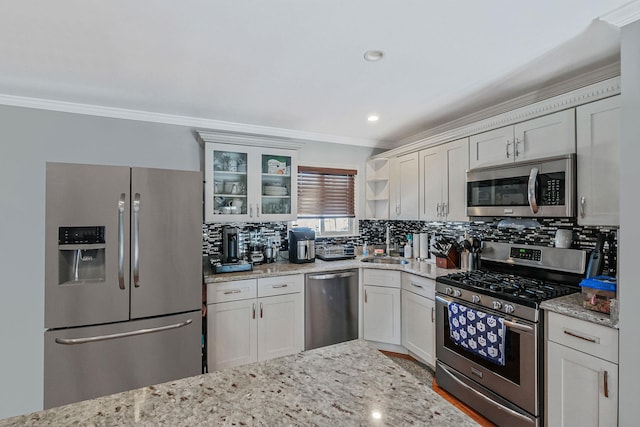 kitchen with backsplash, ornamental molding, white cabinets, and appliances with stainless steel finishes