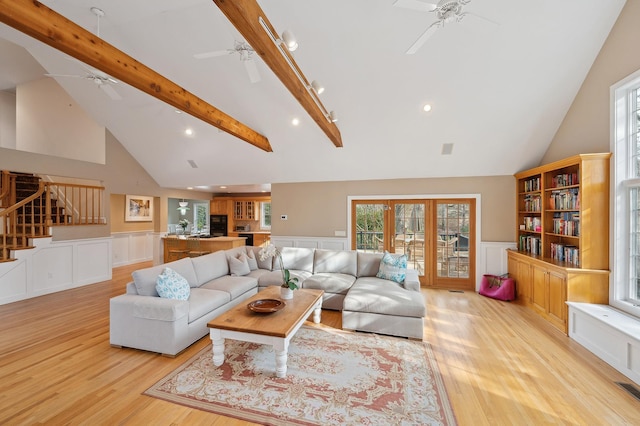 living area featuring ceiling fan, stairway, beamed ceiling, and light wood finished floors