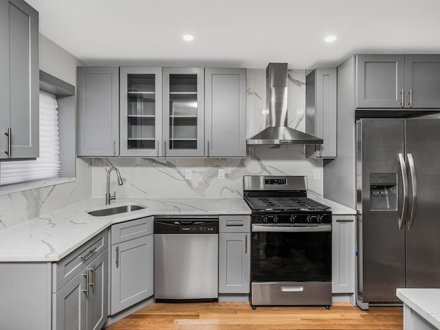 kitchen featuring wall chimney exhaust hood, stainless steel appliances, and gray cabinetry