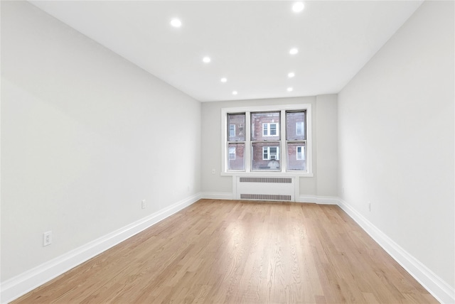 unfurnished room featuring light hardwood / wood-style floors and radiator heating unit