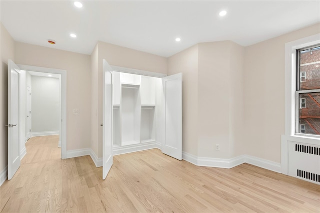 unfurnished bedroom featuring radiator heating unit and light wood-type flooring