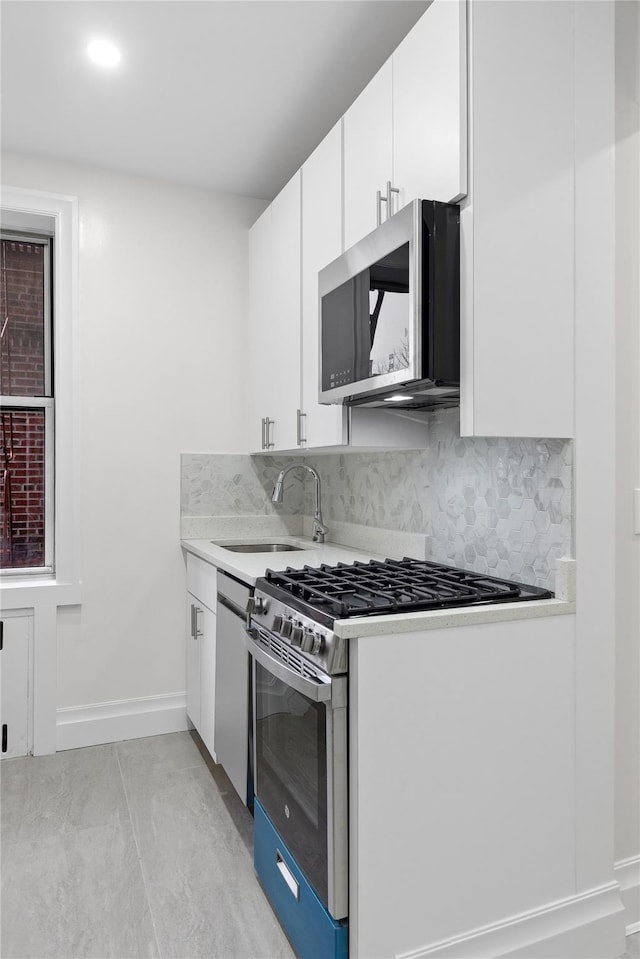 kitchen featuring decorative backsplash, sink, stainless steel appliances, and white cabinets