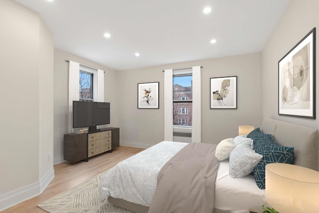 bedroom featuring multiple windows, light hardwood / wood-style flooring, and radiator