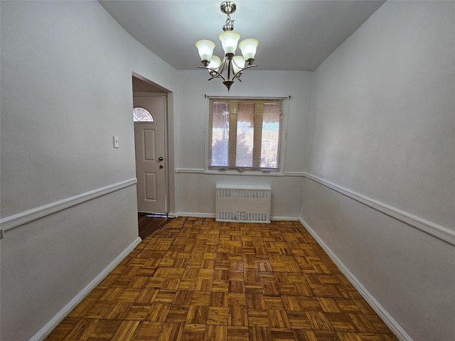 unfurnished dining area featuring a chandelier, radiator, and dark parquet floors