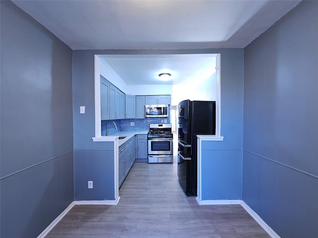 kitchen with appliances with stainless steel finishes, sink, hardwood / wood-style floors, and decorative backsplash