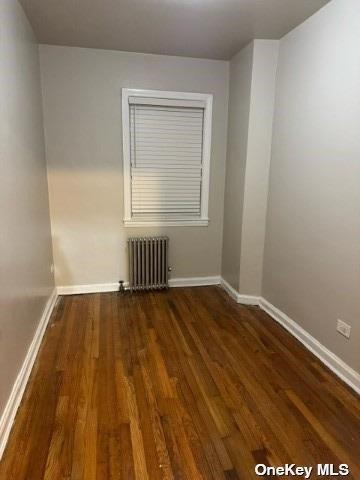 empty room with radiator and dark hardwood / wood-style floors