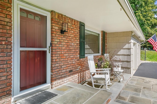 property entrance featuring a porch and brick siding