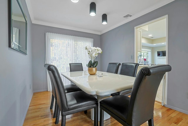 dining area with visible vents, crown molding, and light wood finished floors