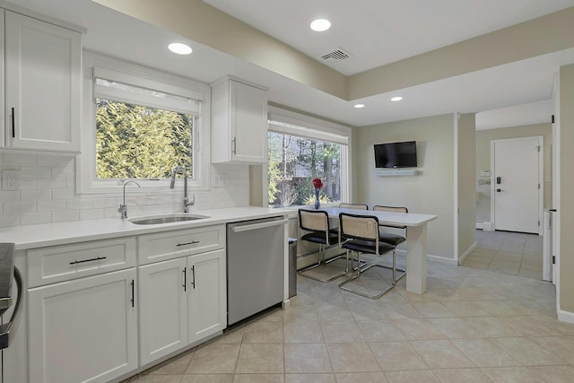 kitchen featuring a sink, visible vents, light countertops, stainless steel dishwasher, and tasteful backsplash