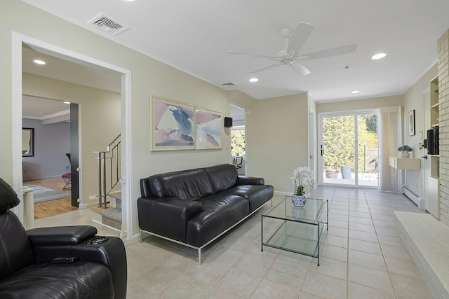 living room featuring visible vents, stairs, baseboard heating, a fireplace, and light tile patterned flooring