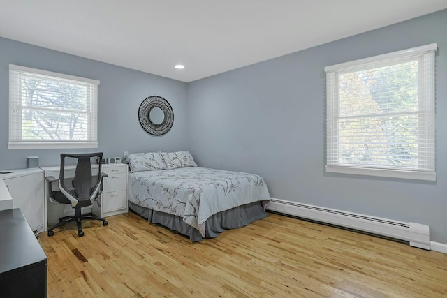 bedroom featuring light wood finished floors, a baseboard radiator, multiple windows, and recessed lighting