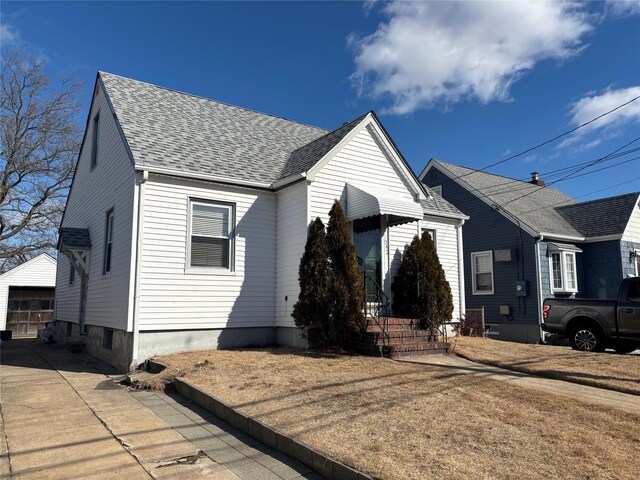 bungalow-style house featuring driveway, a shingled roof, and a detached garage