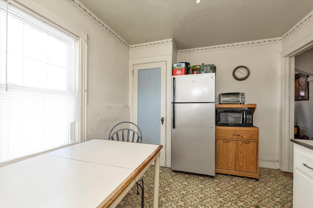 kitchen featuring stainless steel fridge and tile walls