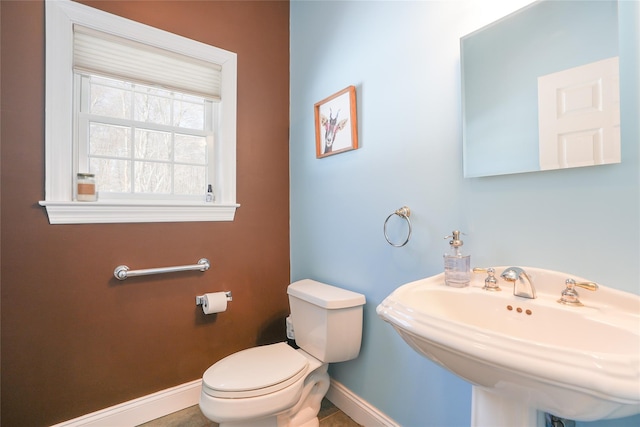 half bathroom featuring toilet, baseboards, and a sink