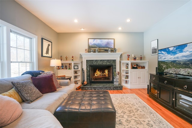 living room featuring light wood-style floors, a premium fireplace, and recessed lighting