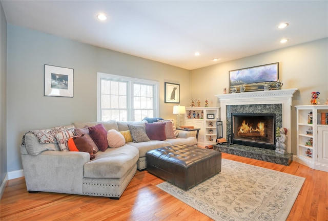 living room with recessed lighting, a high end fireplace, and light wood-style floors