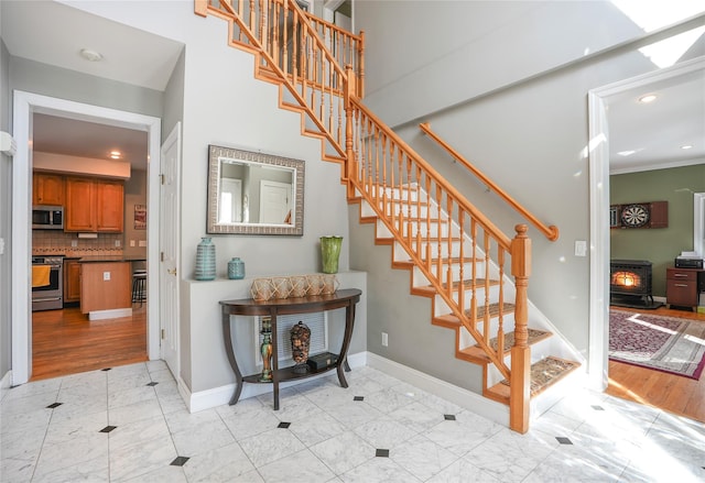 stairway featuring a wood stove, baseboards, and recessed lighting