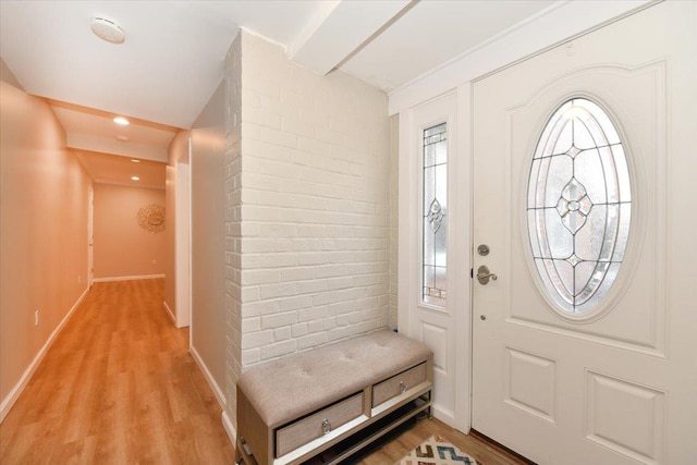 foyer entrance with baseboards, light wood-style flooring, and brick wall