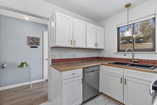 kitchen featuring a sink, white cabinetry, marble finish floor, stainless steel dishwasher, and decorative light fixtures