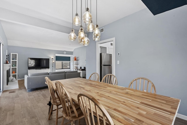 dining space featuring wood finished floors, visible vents, and baseboards