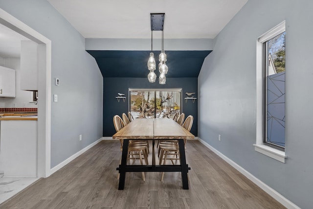 dining area featuring a chandelier, wood finished floors, and baseboards