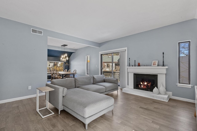 living room featuring baseboards, a fireplace, visible vents, and wood finished floors