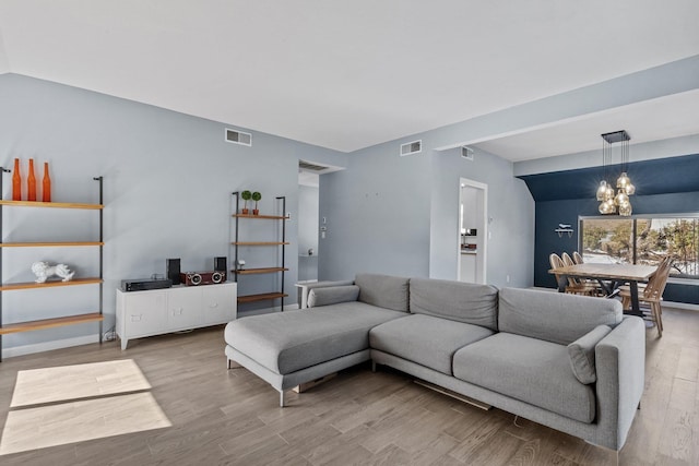 living area with wood finished floors, visible vents, and an inviting chandelier