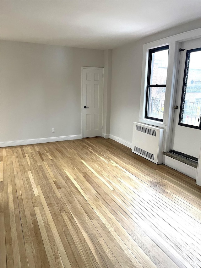 empty room featuring radiator heating unit and light hardwood / wood-style floors