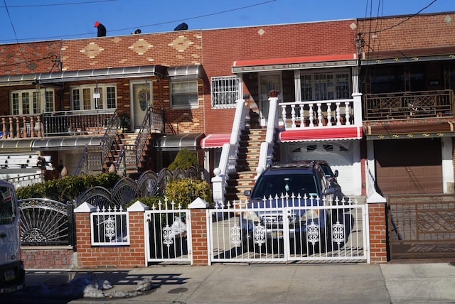 view of front facade with an attached garage, brick siding, a fenced front yard, and a gate