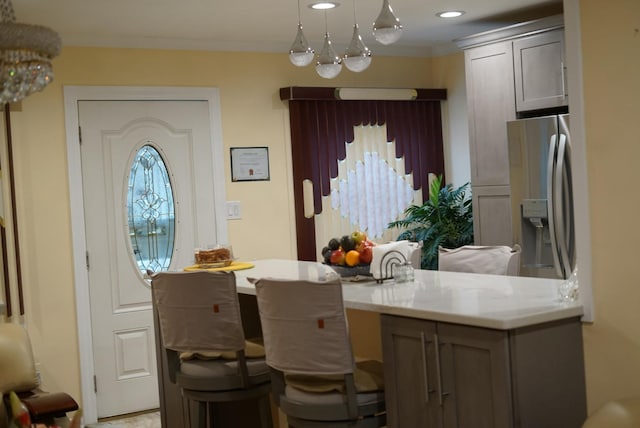 kitchen with stainless steel fridge with ice dispenser, ornamental molding, decorative light fixtures, and a breakfast bar area