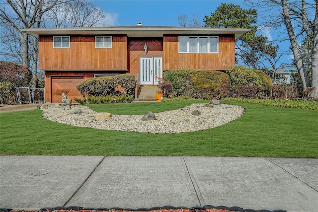 bi-level home with an attached garage, a front yard, and fence